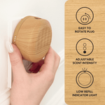 Close-up of a wood-finish Scent Theory plug-in diffuser being rotated into a wall outlet with feature icons at right