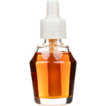 Studio close-up of a clear glass amber fragrance oil refill bottle with visible liquid and a white plastic screw-on cap.