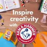 Desk with school supplies, science props and Arm & Hammer logo plus a small baking soda box and 'Inspire creativity' text
