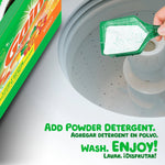 Top-down view of a laundry machine tub with a green scoop of Gain powder detergent being added from a box at the frame edge