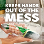 Person cleaning inside a glass with a Scotch‑Brite dishwand, foam on the pad and text overlay stating 'Keeps hands out of the mess.'