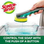Hand-held Scotch-Brite dishwand dispensing soap into a glass dish, logo and faucet visible in lifestyle scene