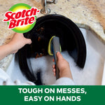 Top-down lifestyle image of dishwashing with a Scotch-Brite dishwand cleaning a large black plate in soapy sink