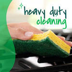 Hand holding a Scotch-Brite heavy duty sponge scrubbing a stovetop with 'heavy duty cleaning' text overlay.