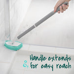 Person using the extended gray handle and green pad to clean the corner of a shower, demonstrating reach and handle extension.