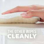 Side view close-up of a hand holding a dual-layer Scotch-Brite Greener Clean pad showing scrub and wipe layers