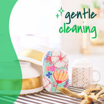 Floral-patterned pop-up sponge standing on a drying rack next to dishes with overlay text reading gentle cleaning.