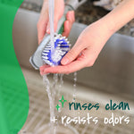 Close-up of hands rinsing a Scotch-Brite dishwand brush head under running water at a sink