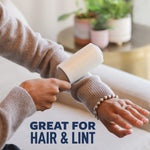 Close-up of hands using a Scotch-Brite lint roller on a sweater sleeve with potted plants blurred in the background.