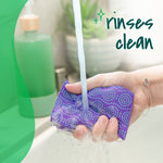 Hand holding a purple Scotch-Brite sponge under running tap water with text overlay that reads rinses clean
