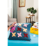 Lifestyle photo of a hand spraying Scotchgard Fabric Crafts onto a decorative pillow in a living room craft setting.