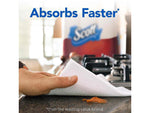 Hand using a Scott paper towel to wipe a countertop with Scott packaging blurred in background