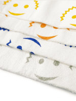 Close-up stacked view of white Scrub Daddy cloths showing smiling face and zigzag printed patterns in multiple colors.