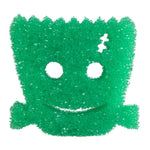 Close-up of a green Scrub Daddy Halloween sponge shaped like a Frankenstein head with smile and round eye holes.