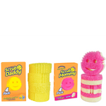 Two orange Scrub Daddy and Scrub Mommy boxes with stacks of yellow and pink smiling scrub sponges on white background