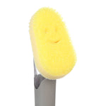 Close-up of the yellow Scrub Daddy smiling sponge head mounted on the dishwand, textured foam surface clearly visible.