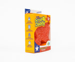 Angled view of Scrub Daddy yellow retail box showing Texas-shaped orange flex-texture scrubber through front window