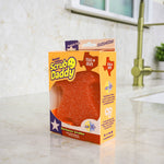 Scrub Daddy special edition Texas-shaped sponge in its yellow retail box placed on a kitchen countertop near a sink