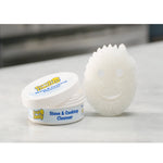 Lifestyle photo of Scrub Daddy Stove & Cooktop Cleanser tub and a white smile sponge on a countertop