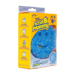 Angled view of Scrub Mommy packaging with a blue snowflake-shaped sponge visible through the front window and usage icons on the side panel.