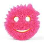 Close-up of a pink porous ResoFoam Scrub Mommy smile-face sponge against a white background.