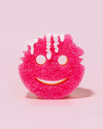 Pink Scrub Mommy sponge standing upright with white foam dripping over the textured scrub surface