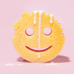 Yellow Scrub Mommy sponge face with white liquid drips displayed upright on a pink background with small puddles