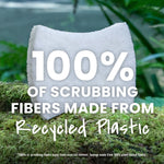 White scrub sponge placed on moss with large text overlay stating “100% of scrubbing fibers made from Recycled Plastic”