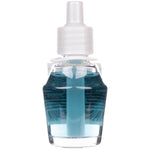 Close-up of a clear glass refill bottle filled with pale blue oil and a white plastic cap against a white background