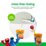 Rinse cup and toothbrush staged by a faucet to show mess-free rinsing; cup and cap feature Sesame Street character graphics
