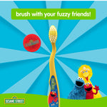 Yellow toothbrush centered on blue burst background with travel cap and Sesame Street characters Cookie Monster, Big Bird, and Elmo