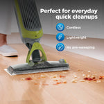 Shark VACMOP in use on a hardwood floor picking up crumbs with overlay icons highlighting cordless and lightweight features