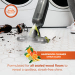 Close view of a Shark VACMOP head spraying cleaner on a tiled floor with citrus fruit graphic and product benefit text