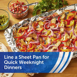 Sheet pan lined with crinkled aluminum foil holding roasted vegetables and chicken, styled food shot