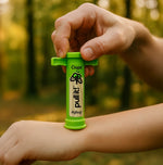 Lifestyle photo of a hand holding a green Shübug Pull It! device pressed to a forearm in an outdoor setting