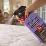 Hand spraying a purple Shubug bed bug killer bottle with black trigger over a mattress, mist visible from the nozzle