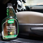 Simoniz all-purpose cleaner bottle on a car interior door panel next to a fabric seat, label clearly visible.