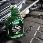 Simoniz green all-purpose cleaner bottle placed on an engine cover inside a car engine bay, label facing forward.