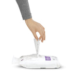 Hand pulling a sheet from a flat simplehuman dispenser pack of white drawstring trash bags on a white background
