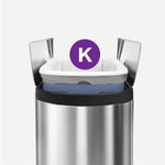 Stainless steel simplehuman trash can with an open lid and a fitted white drawstring bag marked by a purple 'K'.