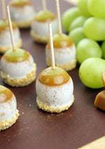 Small round desserts or cheese balls skewered with wooden toothpicks next to green grapes