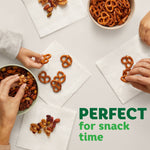 Overhead view of snacks and pretzels placed on white napkins, hands reaching in, 'Perfect for snack time' text
