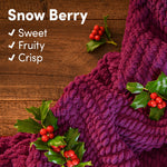 Close-up of purple knit fabric and holly sprigs with text describing Snow Berry scent as sweet, fruity, crisp