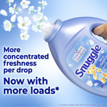 Tilted Snuggle Blue Sparkle bottle pouring scent with floral petals and text about concentrated freshness and more loads