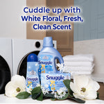 Styled laundry scene with Snuggle liquid bottle, dryer sheets and fabric spray displayed with floral accents