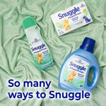 Flat lay of Snuggle SuperFresh Morning Breeze product range on green fabric including spray box and liquid bottle