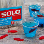 Packed Solo cups on a wooden surface with filled clear cups of blue jelly and gummy fish around them
