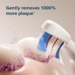 Close-up lifestyle-style image of a Sonicare toothbrush head brushing along teeth with plaque particles