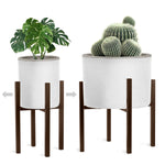 Two brown mid-century metal plant stands shown at different widths holding white planters with greenery on a white background.