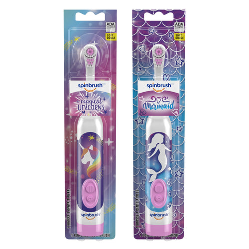 Two packaged Spinbrush kids electric toothbrushes with unicorn and mermaid handle designs, pink power buttons visible through blister cards.